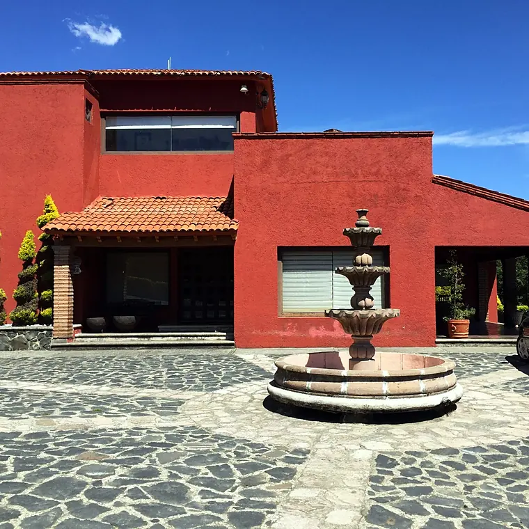 Residencia en Lomas de Ajusco con fachada roja y fuente en el patio