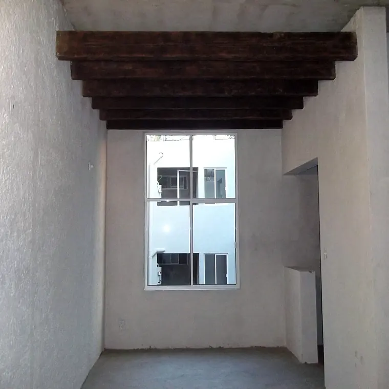 Interior con vigas de madera de las 7 viviendas rehabilitadas en Roma Norte